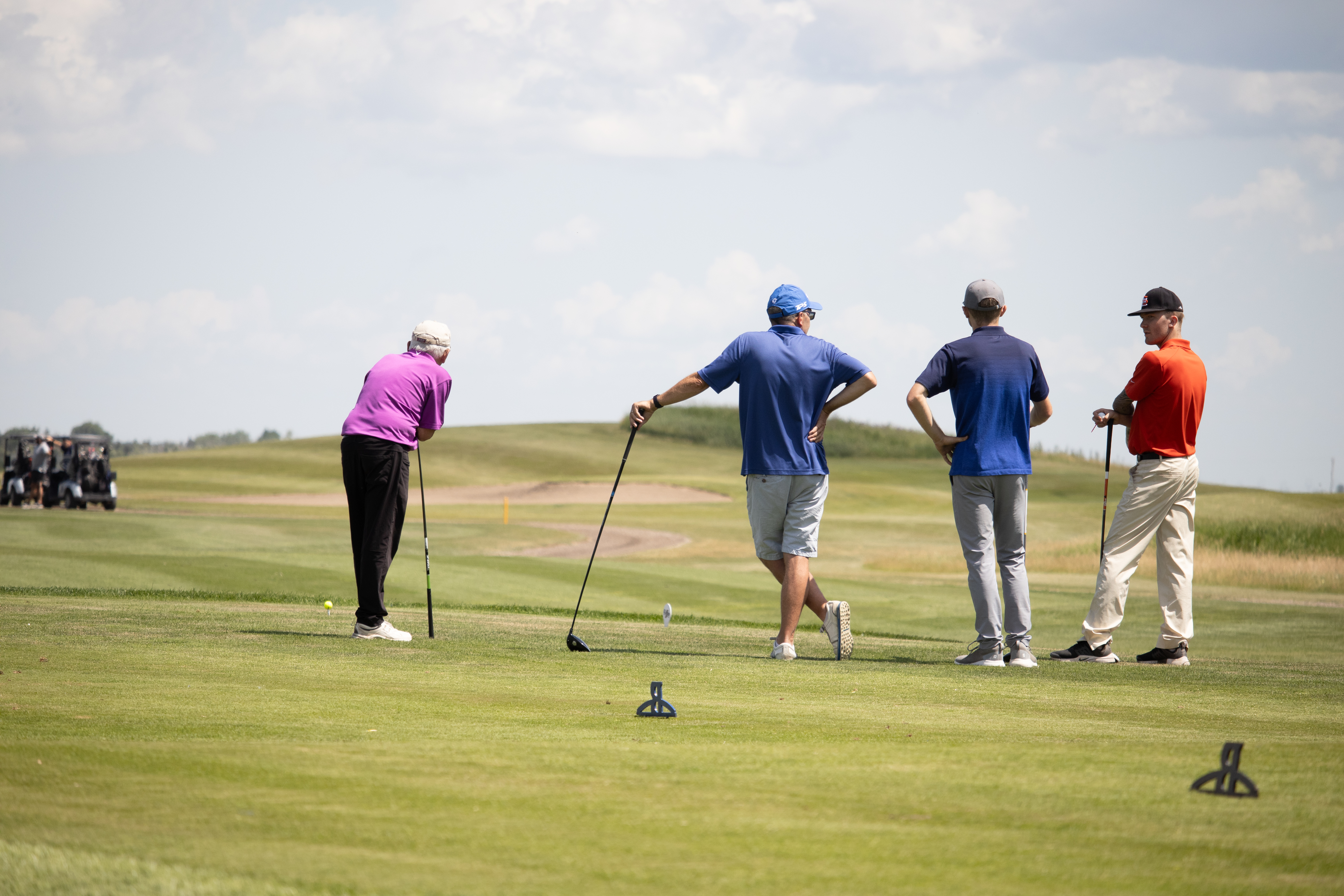 Four golfers stand at the tee during the MCC Manitoba Golf Tournament at Bridges Golf Course