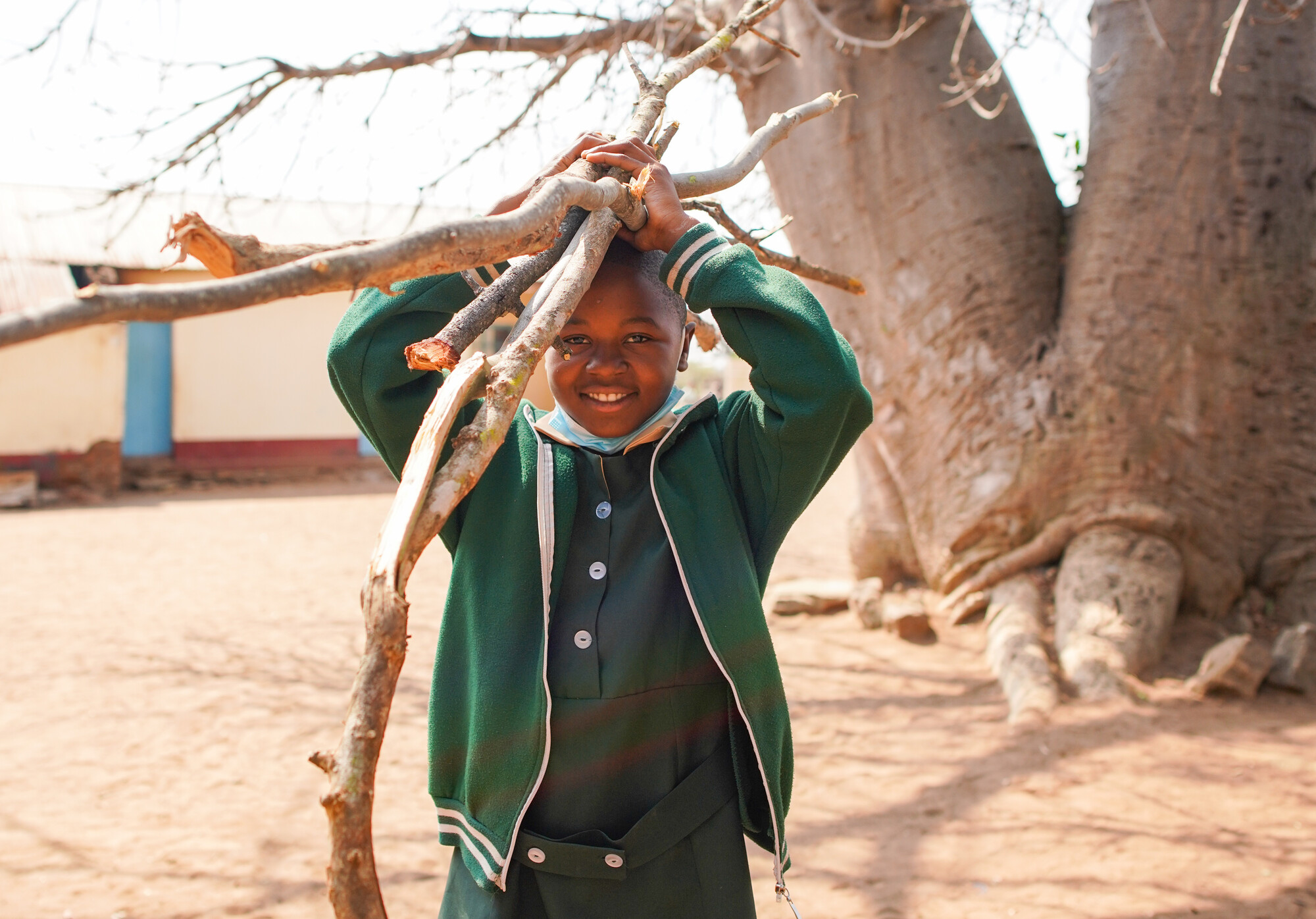 Danaishe Mutausi, 11, carrying one piece of firewood. The children used to have to bring four pieces of firewood and now they only have to bring one after a fuel efficent stove was installed at their