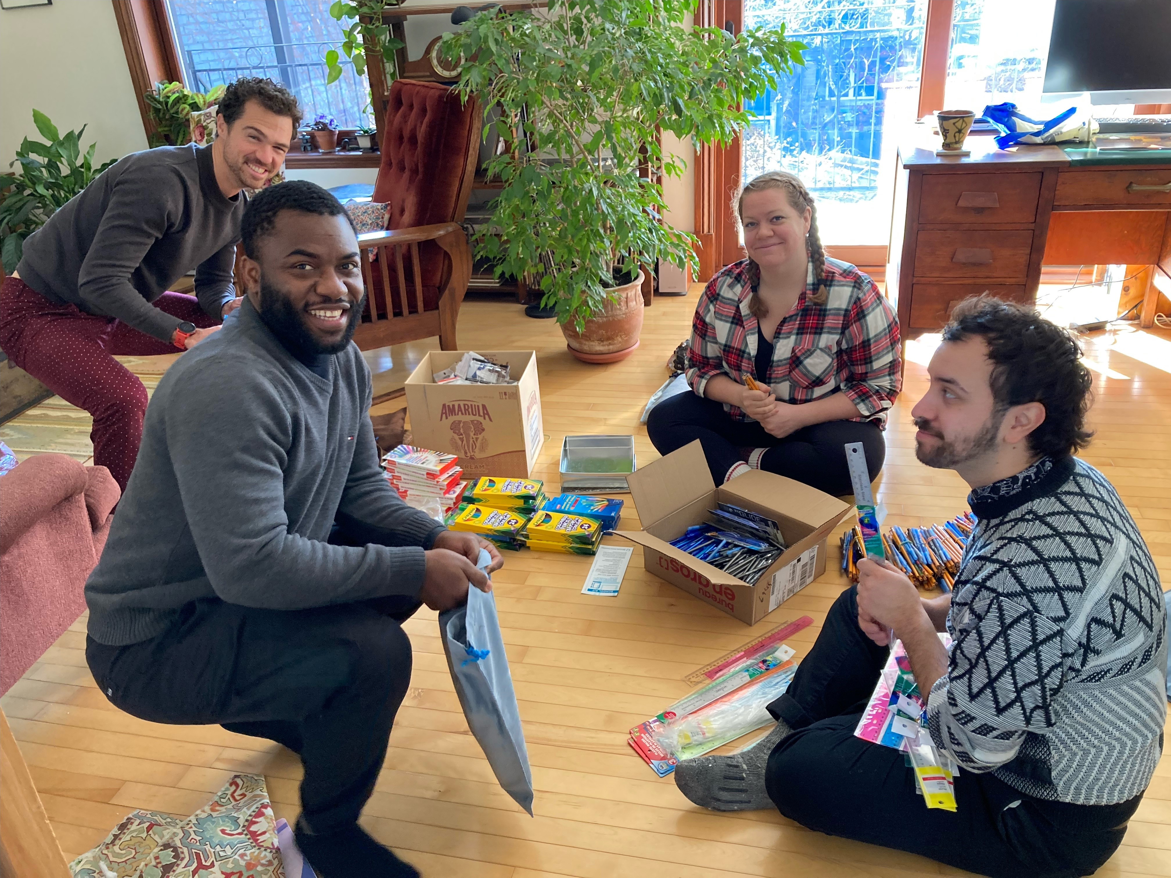 A group of four people smiling for a photo as they pack relief kits