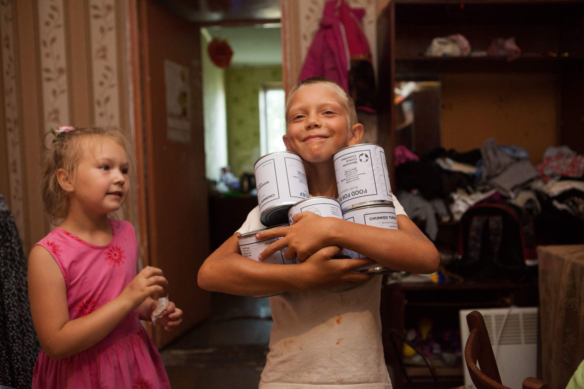A young boy and girl holding cans of meat