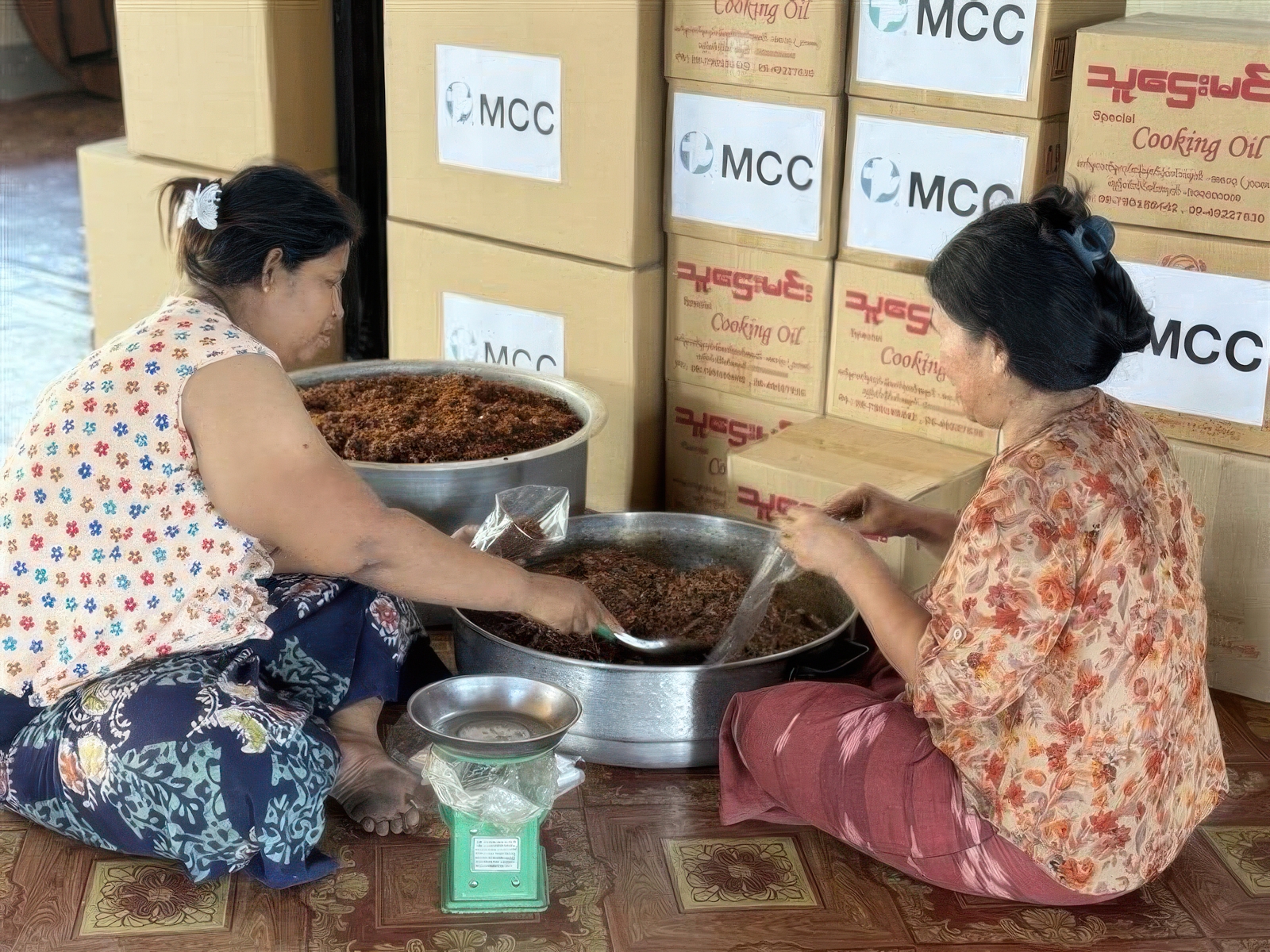 two women preparing food in front of stacks of boxes
