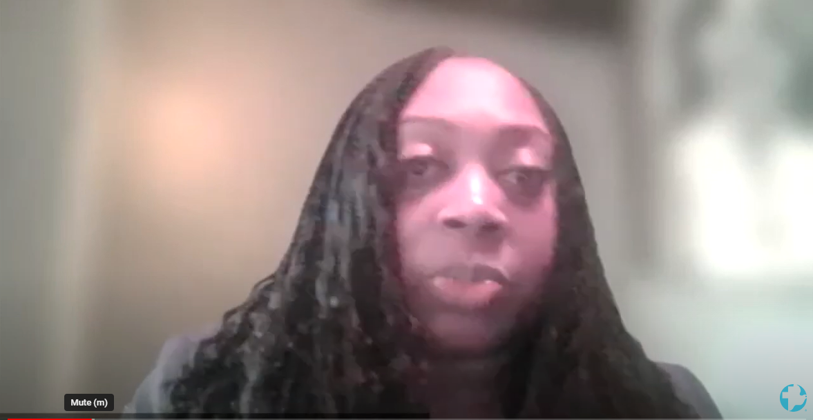 A woman with long hair speaks into the camera on a video call