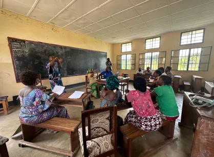 A group of women sitting at desks in a classroom listening to a speaker