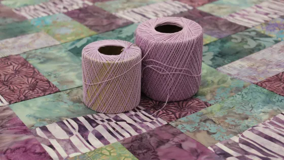 Two spools of thread sit on top of a quilt