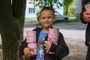 A boy* holds cans of meat he and his mother (not pictured) received from volunteers with MCC partner Association of Mennonite Brethren Churches of Ukraine (AMBCU). The canned meat was part of a distri